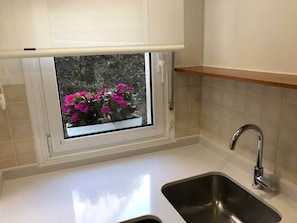 A kitchen with a window, a sink, and a wooden shelf. - COSY APARTMENT closed to RIVERSIDE & Parking (Bilbao)