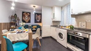 A compact kitchen with a washing machine, oven, and a dining area with a table and chairs. - Inside old town by Eba Homes (Bilbao)
