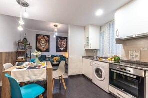 A compact kitchen with a washing machine, oven, and a dining area with a table and chairs. - Inside old town by Eba Homes (Bilbao)