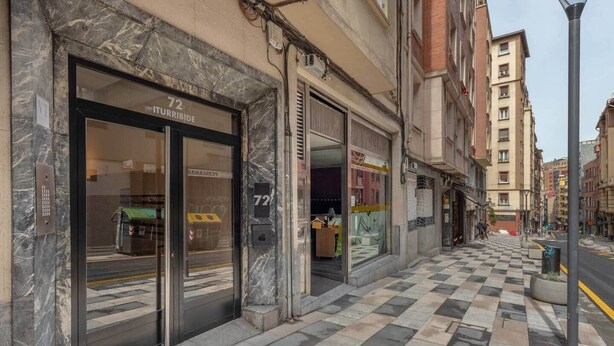 A building with a marble facade, a storefront with glass doors, and a checkered pavement outside. - Inside old town by Eba Homes (Bilbao)