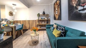 A modern living room with a teal sofa, a coffee table, and a dining area with a wooden table and chairs. - Inside old town by Eba Homes (Bilbao)