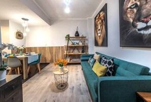 A modern living room with a teal sofa, a coffee table, and a dining area with a wooden table and chairs. - Inside old town by Eba Homes (Bilbao)