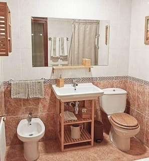 A bathroom with a sink, bidet, toilet, and a mirror above the sink.