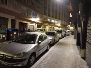 A row of parked cars along a sidewalk in a residential area at night.