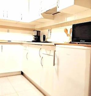 A kitchen with white cabinets, a coffee maker, a microwave, and a toaster.
