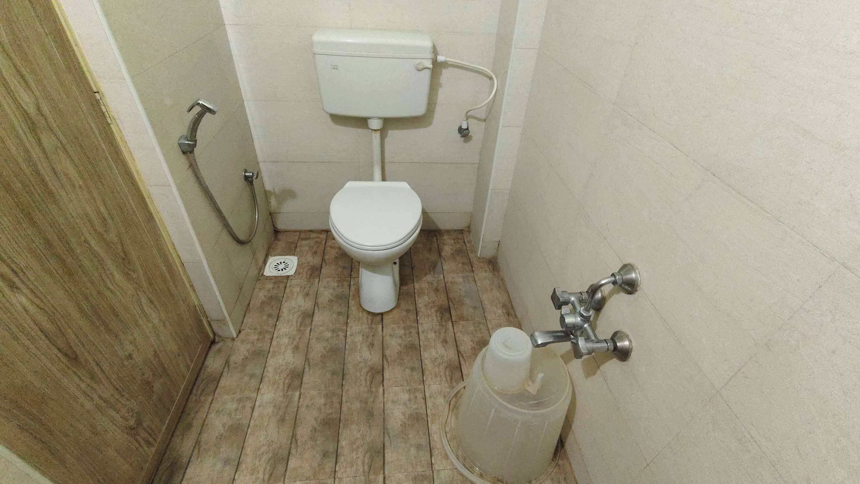 A small, narrow bathroom with a toilet, a shower, and a sink.