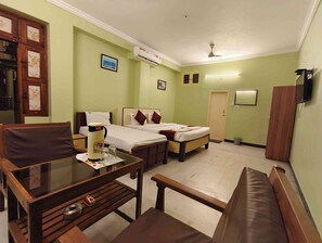 Habitación de hotel con cama, escritorio, silla, sofá, aire acondicionado y televisión.