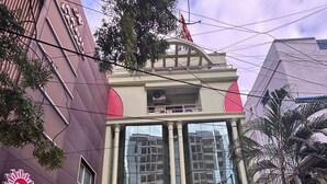 Un edificio con un amplio ventanal de vidrio, una estatua en la parte frontal y un cartel que indica Sunshine Residency.