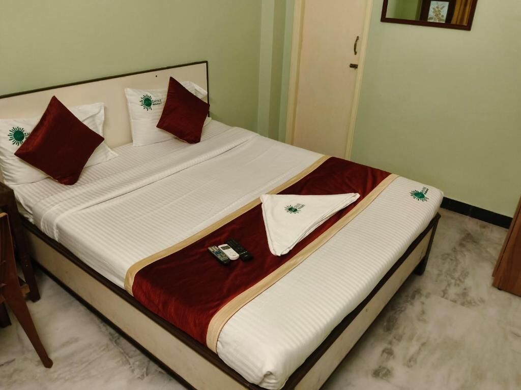 A neatly made bed with a white and red bedspread, two pillows, and a remote control on the bed.
