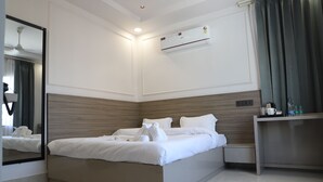 Une chambre d’hôtel moderne équipée d’un grand lit, d’une table de chevet, d’un miroir et d’un appareil de climatisation.