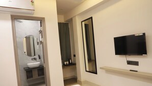 Une chambre d’hôtel équipée d’un lit, d’une télévision, d’un miroir, d’un lavabo et d’une douche.
