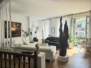 Un salon moderne avec un canapé, une table basse, une cheminée et une grande fenêtre.