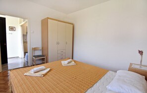 Ein Schlafzimmer mit einem Bett, einem Schrank, einem Sessel und einem kleinen Tisch mit einer Vase.