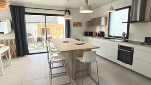Cozinha moderna com ilha central, armários brancos e uma janela grande.