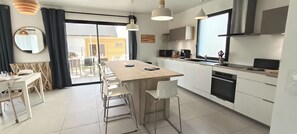 A modern kitchen with a central island, white cabinetry, and a large window. - New house for 13 people. Sandy beach 3 minutes' walk (Bay). Sea views (Saint-Pierre-Quiberon)