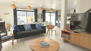 Uma sala de estar moderna com um sofá, poltronas, uma mesa de centro e uma TV.