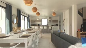 Uma sala de estar moderna com sofá, mesa de jantar para quatro pessoas e televisão.