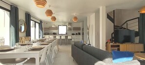 A modern living room with a sofa, dining table set for four, and a TV. - New house for 13 people. Sandy beach 3 minutes' walk (Bay). Sea views (Saint-Pierre-Quiberon)