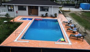 Una piscina al aire libre, sillones reclinables de piscina