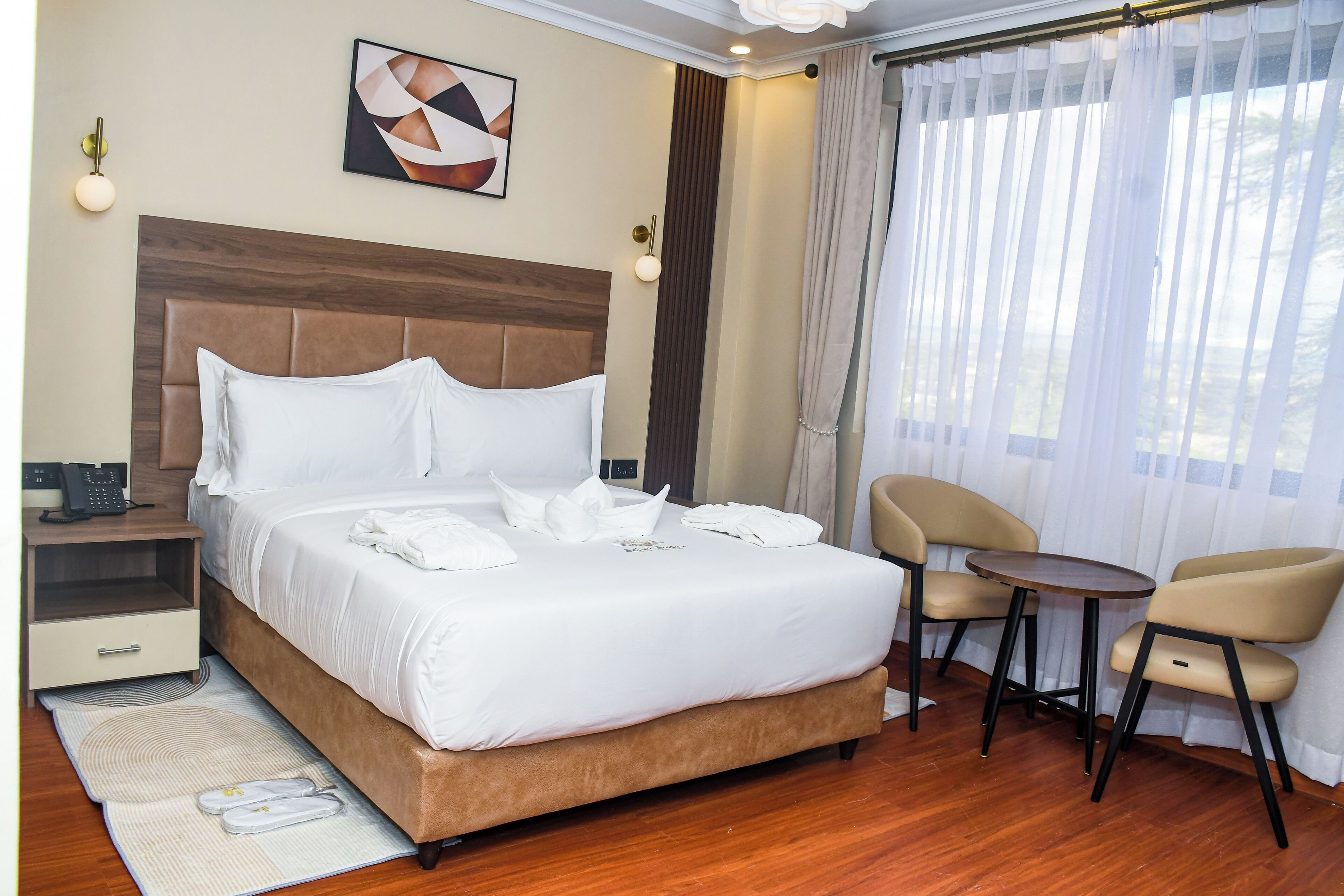Habitación de hotel con una cama grande, mesita de noche, silla, una pequeña mesa y vistas al exterior.