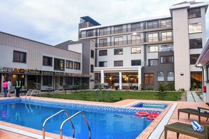 室外游泳池，開放時間為 10:00 至 18:00，提供日光浴躺椅和救生員