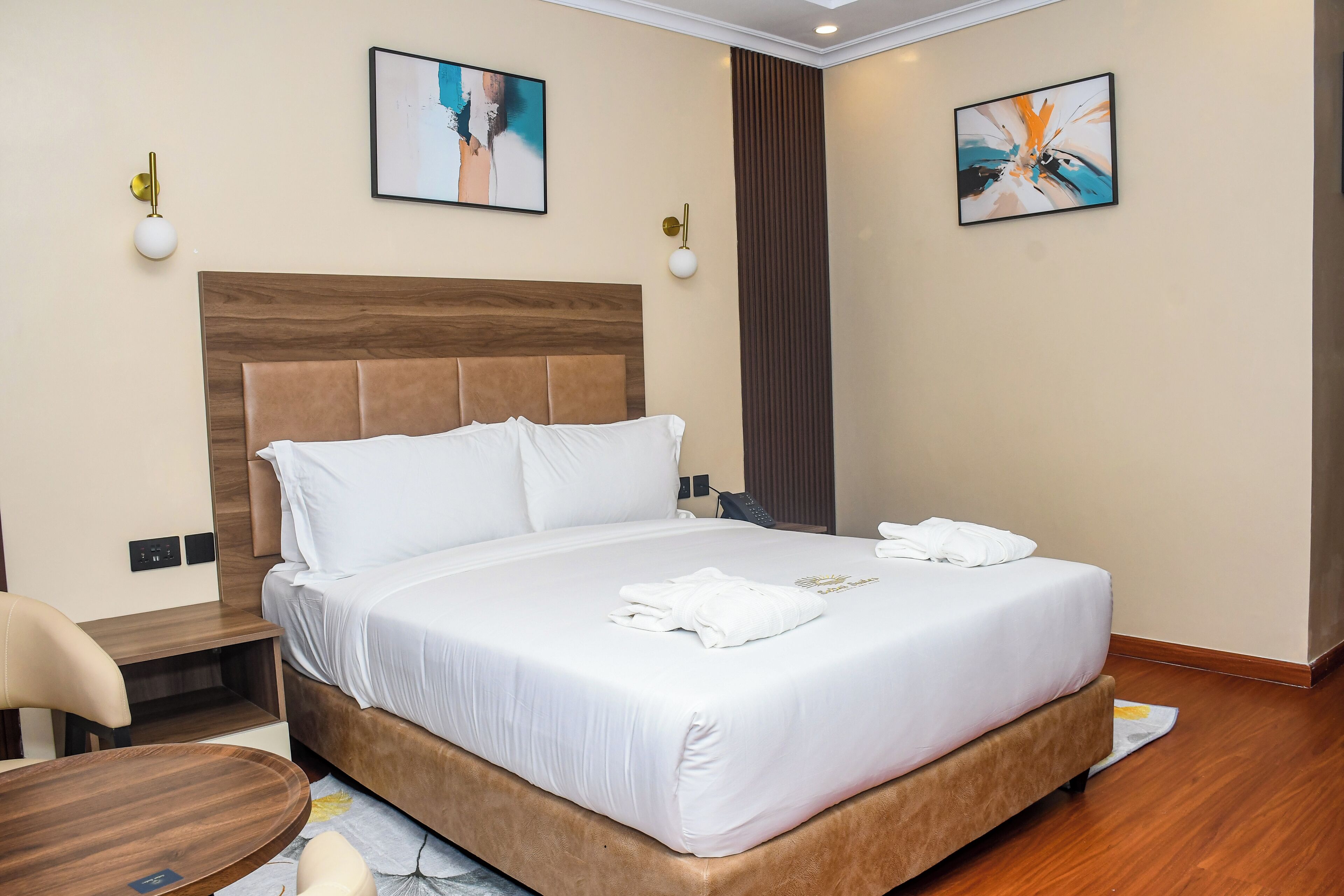 Una habitación de hotel con una cama grande, mesitas de noche, una silla y obras de arte en las paredes.
