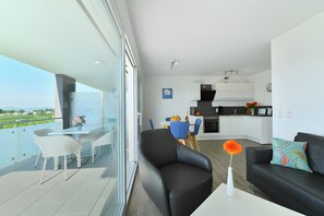 En moderne lejlighed med balkon, spiseområde, opholdsstue og køkken.