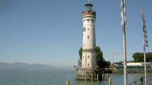 Um farol à beira de águas tranquilas, com céu limpo.