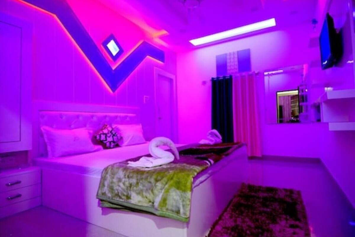 Ein Schlafzimmer mit einem Bett, einem Nachttisch, einem Spiegel und einem an der Wand befestigten Fernseher.