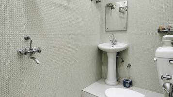 Une salle de bain équipée de toilettes, d’un lavabo, d’une douche et d’un chauffe-eau fixé au mur.