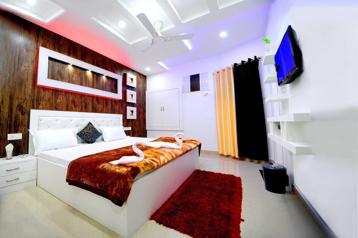Ein modernes Schlafzimmer mit Bett, Nachttischen, Fernseher und Deckenventilator.