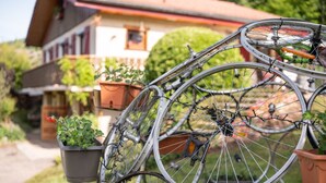 Una bicicleta con canasta y timbre, estacionada frente a una casa con jardín.