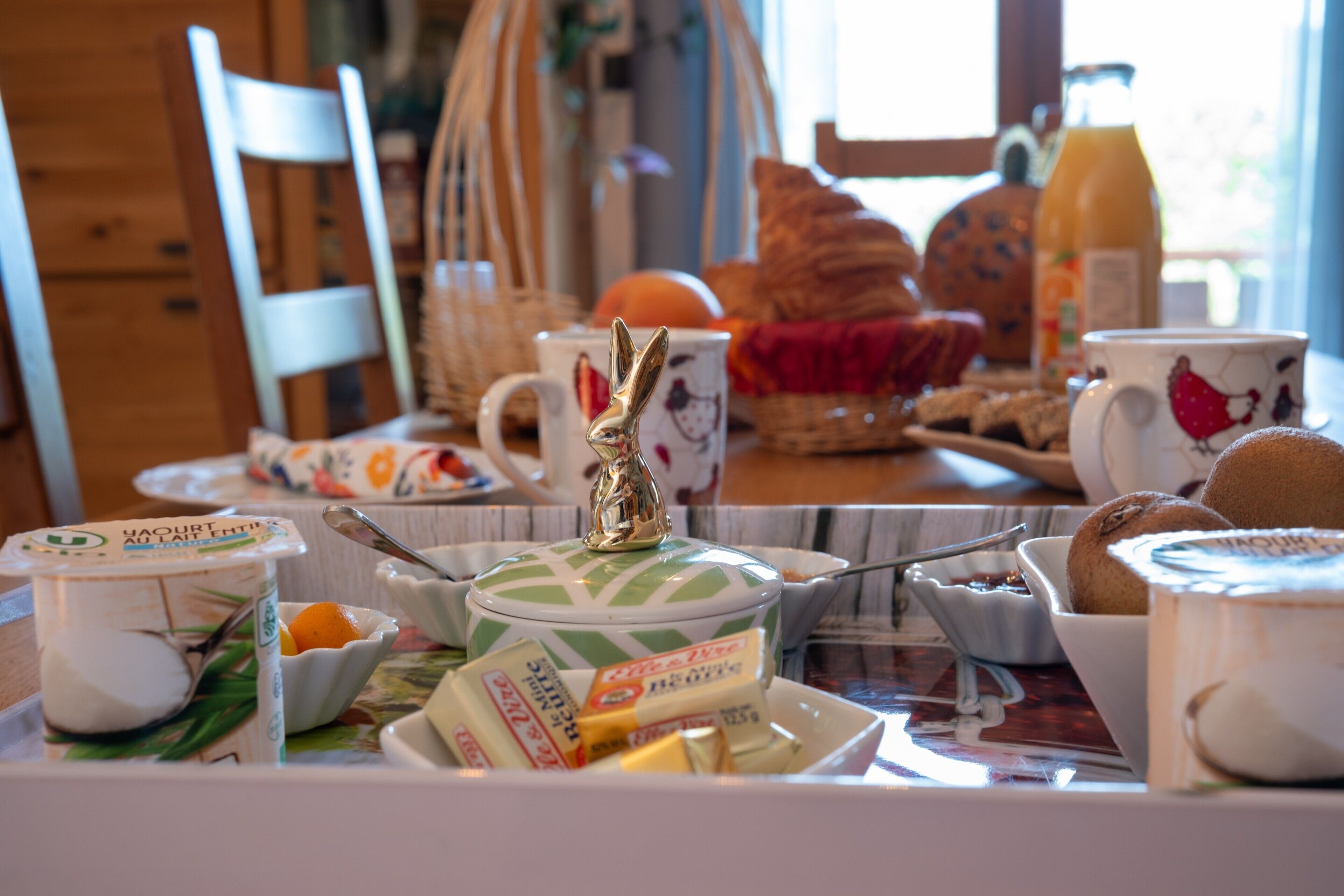 Una mesa de desayuno con diversas opciones de comida, una jarrón y una taza con diseño floral.