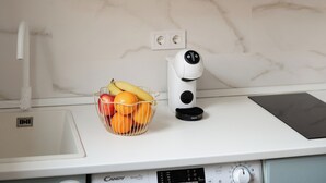 A kitchen with a built-in microwave, a fruit bowl, a coffee machine, and a smart coffee maker. - Mini Apartment Baélia Casa Íbera (Alicante)