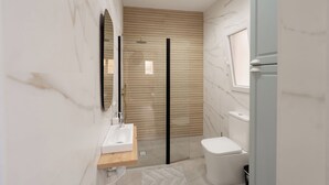 A modern bathroom with a wooden panel wall, a glass shower enclosure, a white toilet, and a wooden vanity with a sink. - Mini Apartment Baélia Casa Íbera (Alicante)
