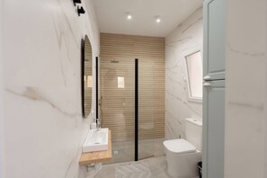 Une salle de bain moderne avec un mur recouvert de panneaux en bois, une douche en verre, des toilettes blanches et un meuble-lavabo en bois avec un évier.