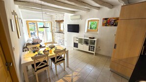 A dining area with a table, chairs, and a TV mounted on the wall. - CROGO Casa Gradinje-Holiday Home-Istria-Motovun (Gradinje)