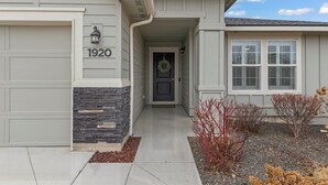 A residential house with a garage, a front door with a wreath, and a stone accent wall.