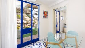 Una habitación con puerta de cristal que da a un balcón, una pequeña mesa con sillas y un suelo con estampado.