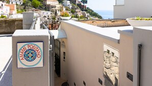 Un estrecho callejón con un letrero que dice 'AMAMI POSITANO' y vistas de edificios costeros.