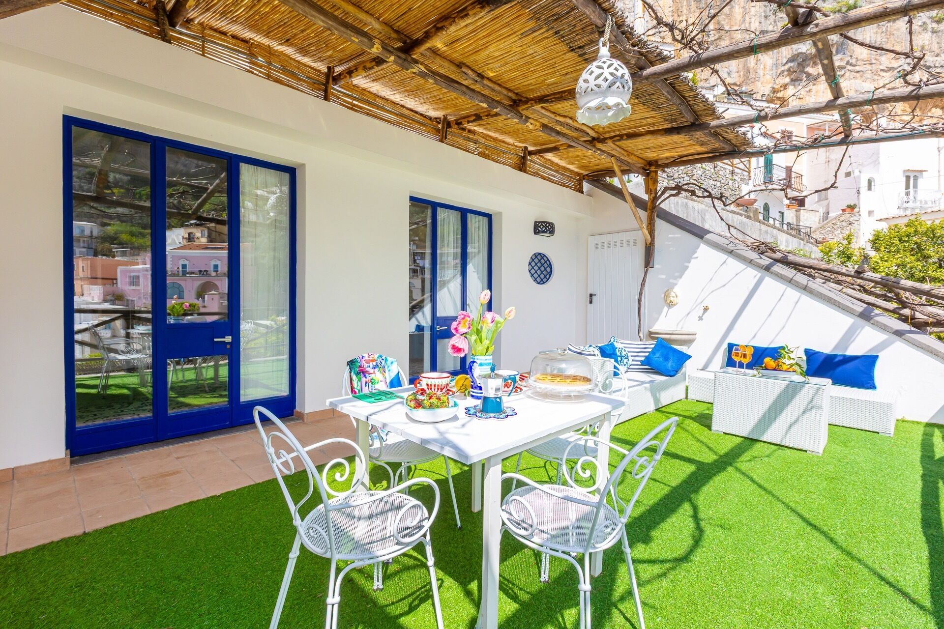 A covered outdoor dining area with a table, chairs, and a sofa.