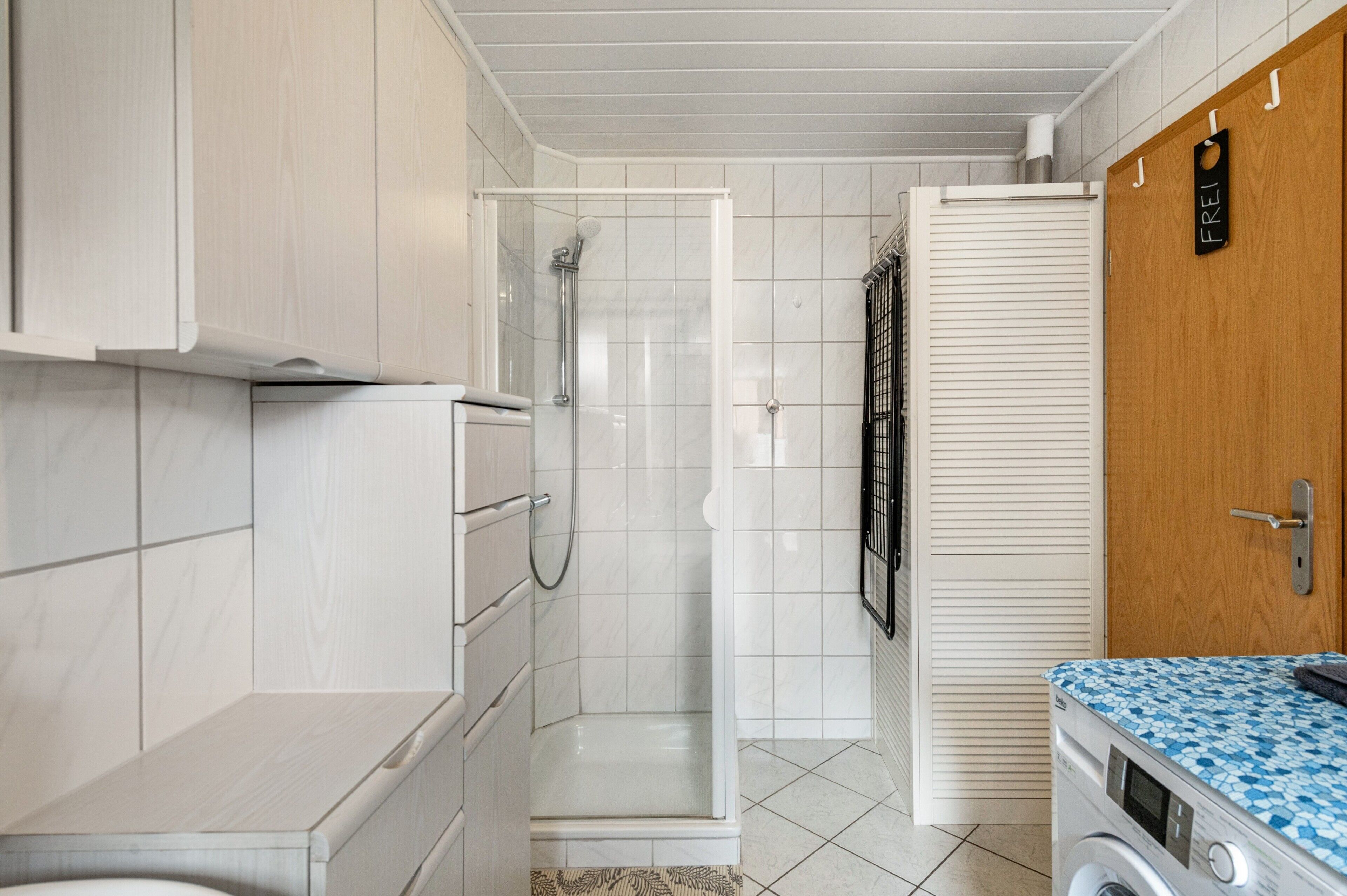 Ein Badezimmer mit Dusche, Toilette und Waschmaschine.