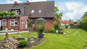 A house with a sloped roof, a garden with a pond, and a well-maintained lawn. - Apartment 'Für 6 Personen 90 M²' with Private Terrace, Shared Garden and Wi-Fi (Siggelkow)