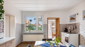 A compact kitchen with a dining area, a window with a view, and a tiled backsplash. - Apartment 'Für 6 Personen 90 M²' with Private Terrace, Shared Garden and Wi-Fi (Siggelkow)