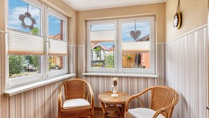 A room with a corner window, wicker chairs, a small table, and a candle holder. - Apartment 'Für 6 Personen 90 M²' with Private Terrace, Shared Garden and Wi-Fi (Siggelkow)
