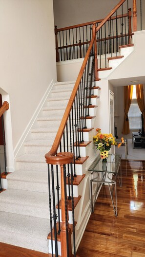 A multi-level wooden staircase with a glass console table and a vase of flowers. - Perfect 5-bedroom House In Charming Fairburn (Fairburn)