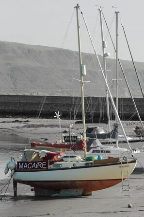 Un bateau nommé MACAIRE était amarré sur une plage de sable, avec un arrière-plan rocheux.