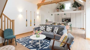 A modern living room with a sofa, a coffee table, and a staircase. - 2 Bed Converted Barn (Ombersley)