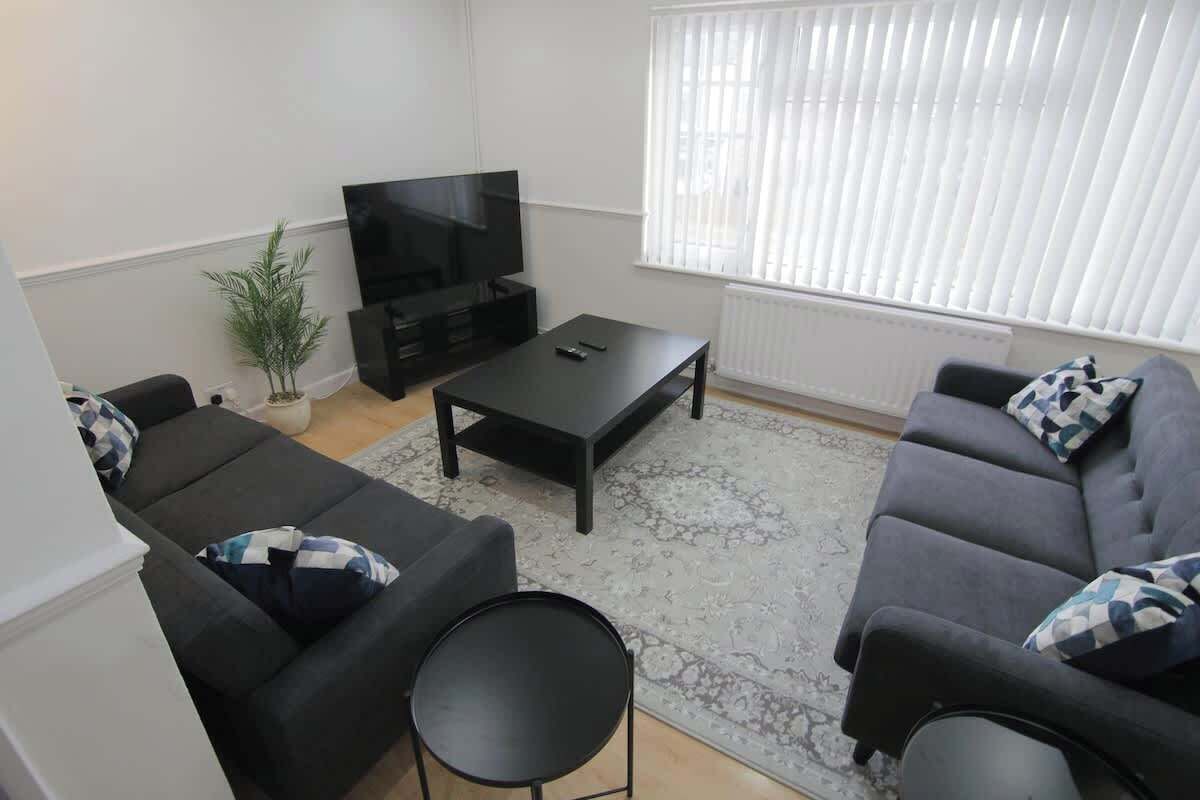 Ein Wohnzimmer mit einer Sofagarnitur, einem Couchtisch, einem Fernseher und einer Topfpflanze.