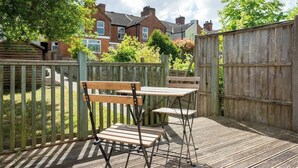 Een houten terras met twee houten banken en een tafel, omgeven door een houten hek.